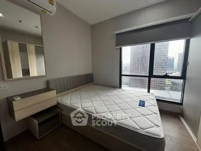 Modern bedroom with large window and city view in high-rise apartment.