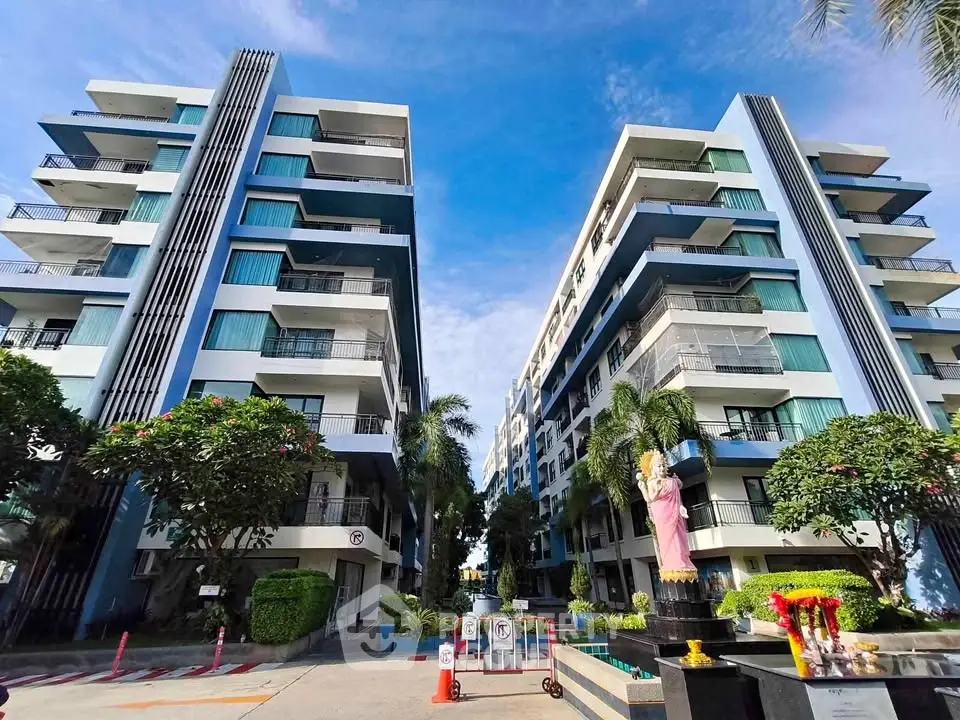 Modern apartment complex with lush landscaping and vibrant blue accents under a clear sky.
