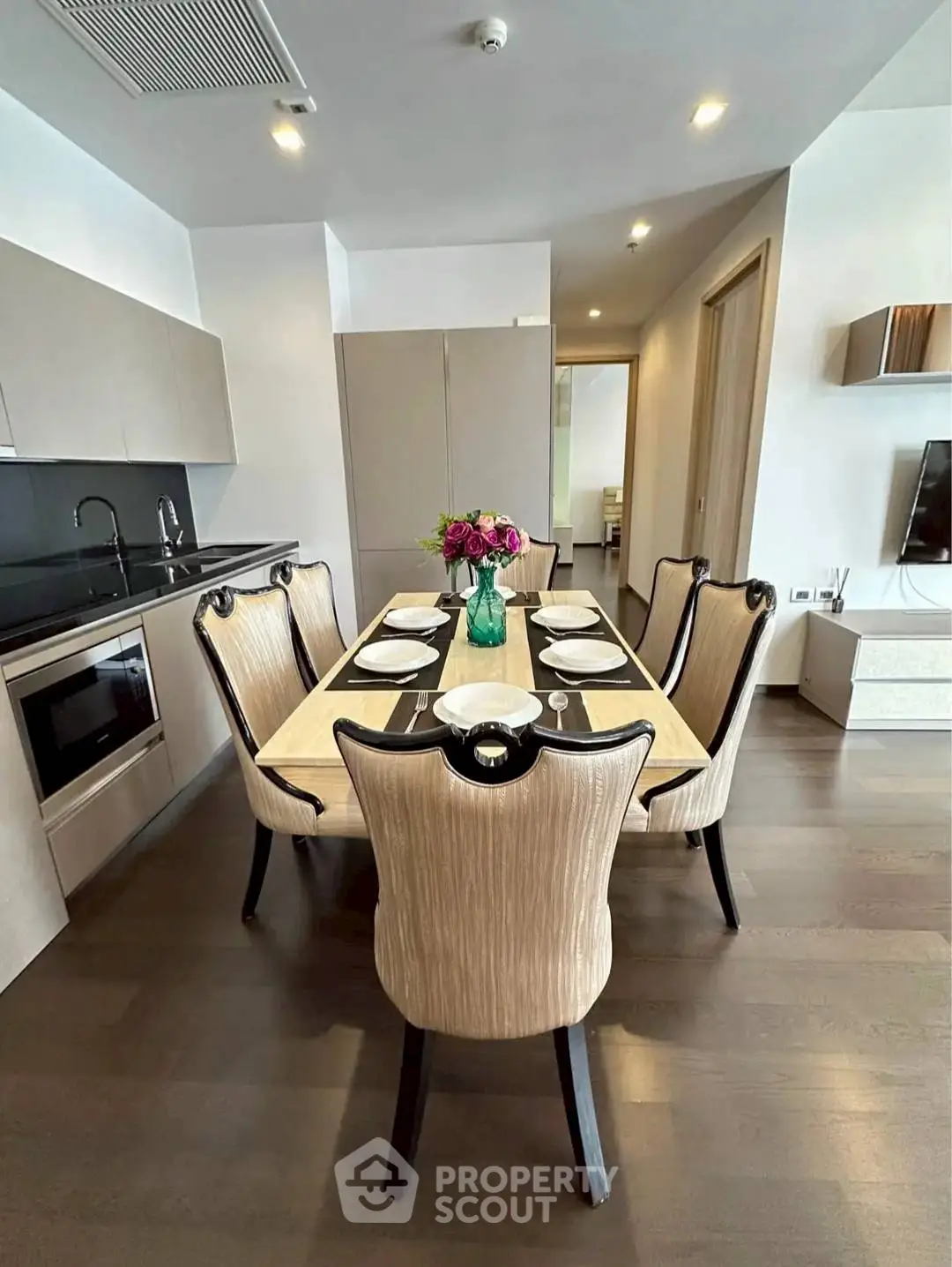 Elegant dining area with modern kitchen featuring sleek cabinetry and built-in appliances.