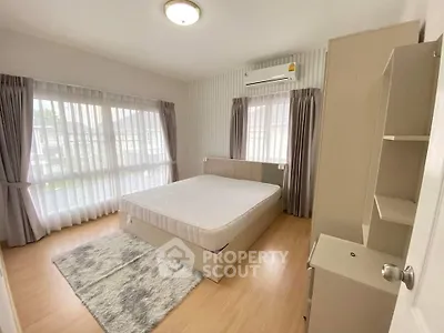 Spacious bedroom with large windows and modern furnishings, perfect for comfort and relaxation.