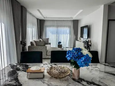 Luxurious modern living room with elegant decor and marble dining table, featuring plush seating and large windows.