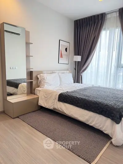 Modern bedroom with stylish decor and large window offering natural light.