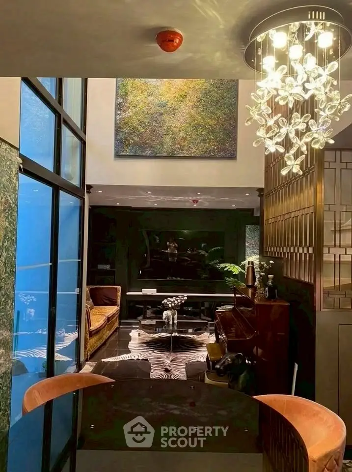 Luxurious living room with high ceiling, elegant chandelier, and modern decor.