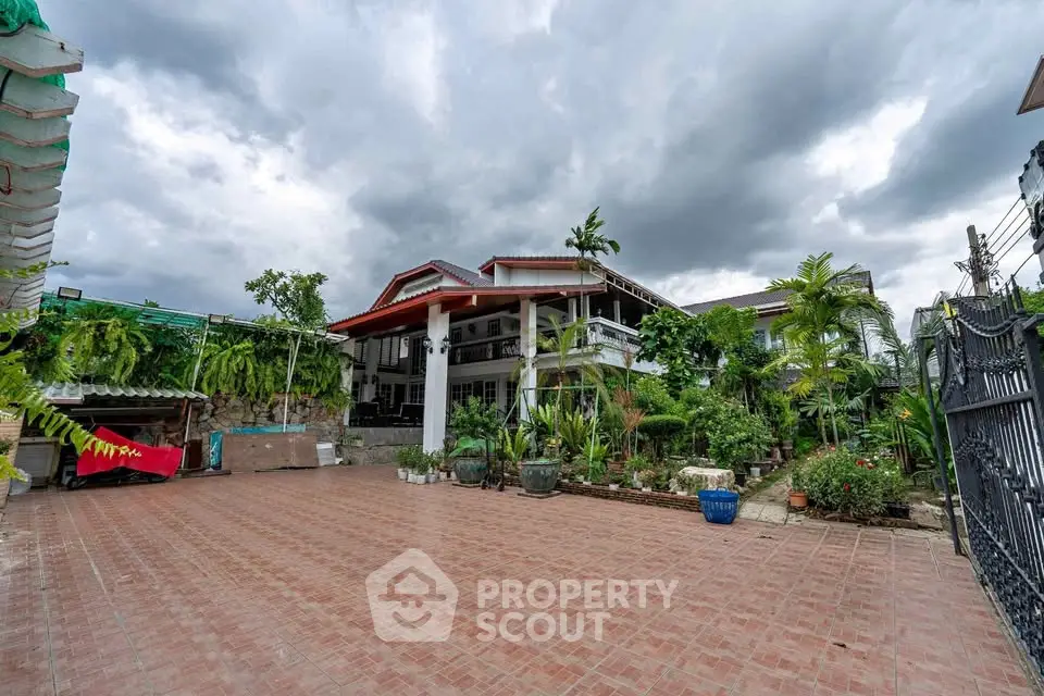Spacious garden view of a luxurious villa with lush greenery and expansive tiled patio.
