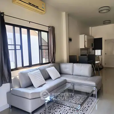 Modern living room with sleek furniture and natural light, featuring a stylish sectional sofa and glass coffee table.