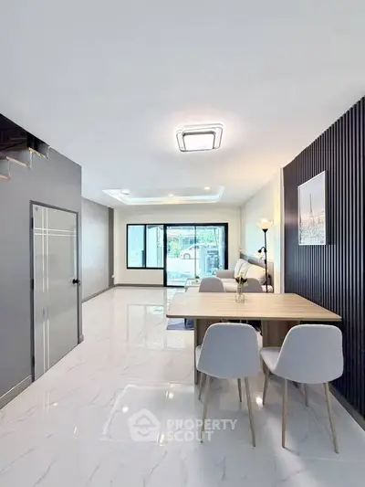 Modern open-plan living room with dining area and large windows for natural light.
