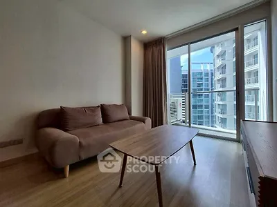 Modern living room with cozy sofa and large window offering city view in high-rise apartment.