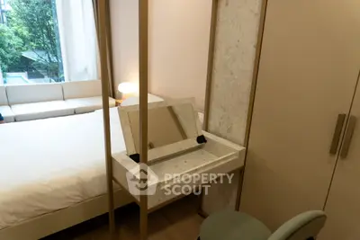 Modern bedroom with stylish vanity and cozy seating area, featuring natural light and elegant decor.