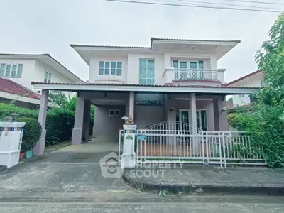Charming two-story house with gated driveway and lush greenery, perfect for family living.