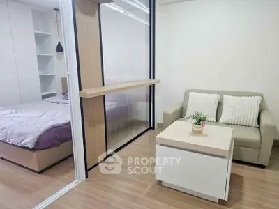 Modern studio apartment with cozy living area and bedroom separated by sliding glass partition.