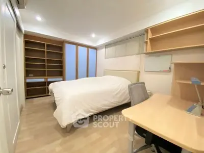 Cozy bedroom with built-in shelves and modern desk, perfect for a comfortable living space.