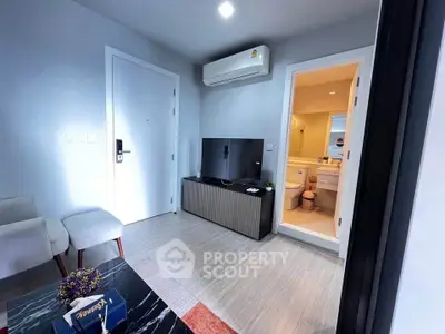 Modern living room with sleek design, featuring a TV, air conditioning, and a glimpse into a stylish bathroom.