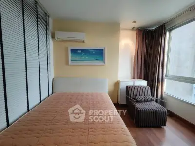 Cozy bedroom with modern decor, featuring a comfortable bed, stylish chair, and large windows for natural light.