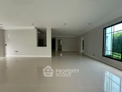 Spacious empty living room with large windows and glossy tiled floor