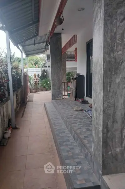 Charming exterior patio with tiled flooring and lush greenery, perfect for relaxation.