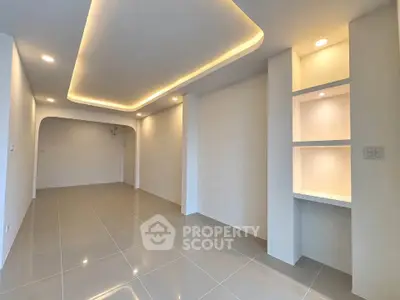 Modern minimalist living room with recessed lighting and sleek tile flooring