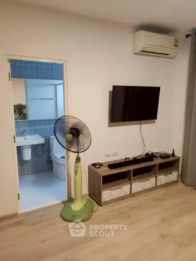 Modern living room with wall-mounted TV and air conditioning, adjacent to a stylish bathroom.