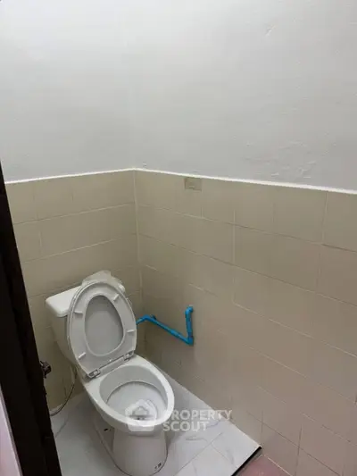 Compact bathroom with tiled walls and a standard toilet, ideal for efficient space utilization.