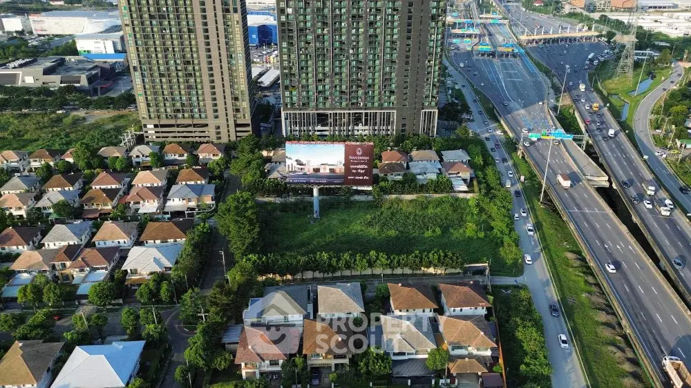 Aerial view of modern high-rise buildings and suburban houses near a highway.