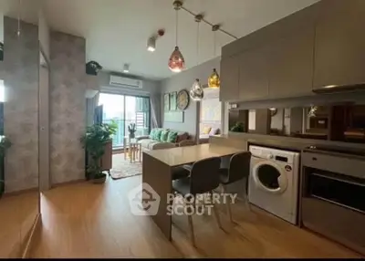 Modern open-plan living room with kitchen, featuring stylish decor and appliances, leading to a balcony with a view.