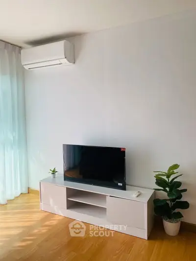 Modern living room with sleek TV stand, air conditioning, and natural light.