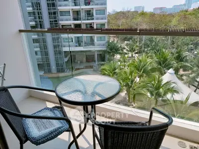 Chic balcony with glass railing offering stunning views of lush greenery and modern buildings.