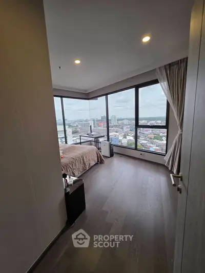 Spacious bedroom with panoramic city view and large windows, offering abundant natural light.