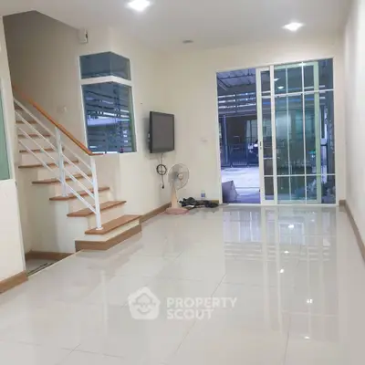 Spacious modern living room with sleek tile flooring and large sliding glass doors.