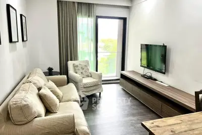 Cozy living room with modern decor and natural light, featuring a comfortable sofa and wall-mounted TV.