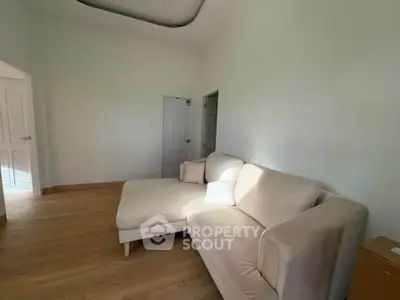 Spacious living room with cozy beige sectional sofa and wooden flooring