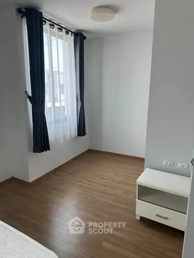 Bright bedroom with wooden flooring and modern curtains, perfect for cozy living.