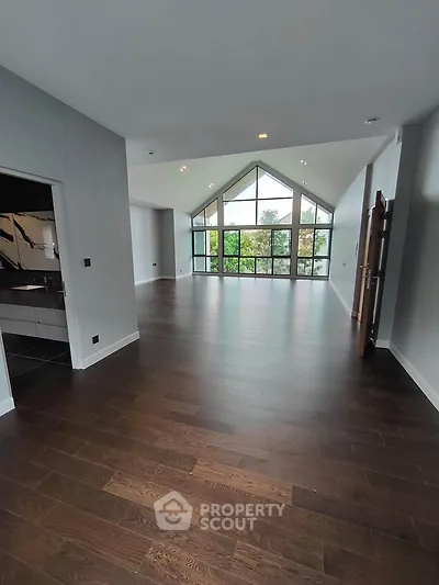 Spacious modern living room with high ceilings and large windows offering natural light and scenic views.