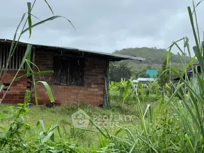 Rural brick house with lush greenery and scenic hill view, perfect for nature lovers seeking tranquility.