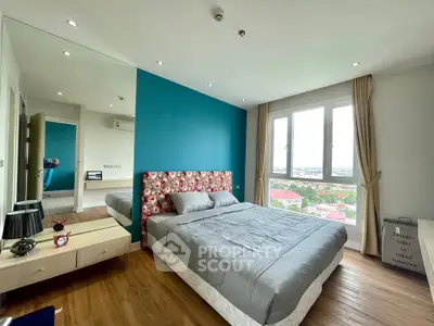 Modern bedroom with blue accent wall and large window offering scenic views.