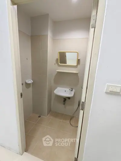 Compact bathroom with beige tiles and wall-mounted sink