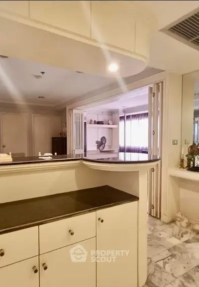 Spacious kitchen with marble flooring and ample storage in modern apartment.