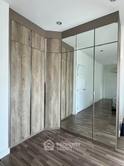 Spacious bedroom with modern mirrored wardrobe and wooden flooring