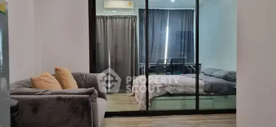 Modern studio apartment with cozy living area and glass partitioned bedroom, featuring stylish decor and natural light.