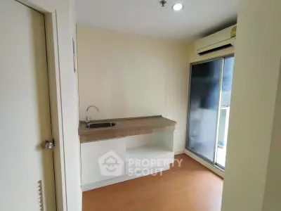 Compact kitchen area with sleek cabinetry and balcony access in modern apartment.