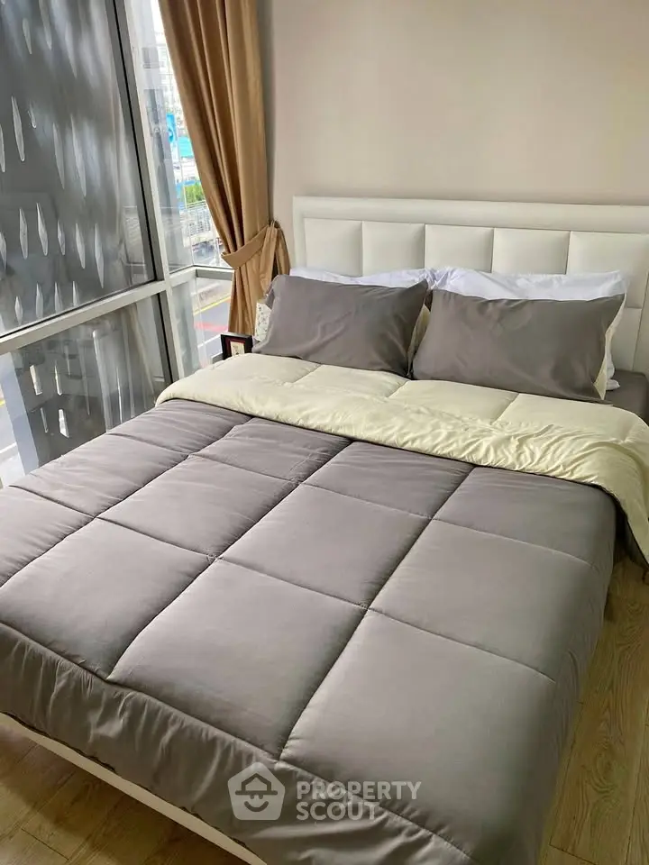 Cozy bedroom with modern decor and large window offering city views.