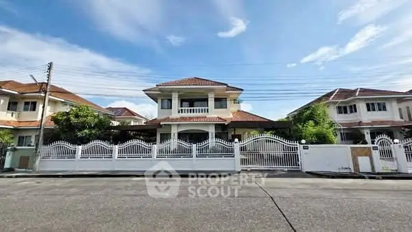Charming two-story house with white fence and red roof under a clear blue sky.