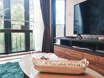 Chic living room with modern TV setup and large windows offering lush garden views.