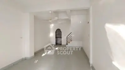 Spacious unfurnished living room with ceiling fan and staircase, ideal for customization.