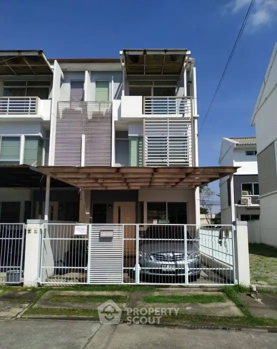 Modern multi-story townhouse with carport and gated entrance in a suburban neighborhood.