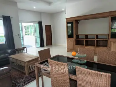 Spacious living room with elegant wooden furniture and glass dining table, perfect for family gatherings.