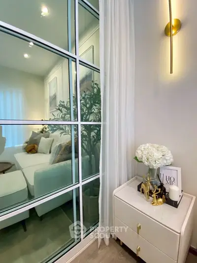 Elegant living room with modern decor and glass partition, featuring cozy seating and stylish lighting.