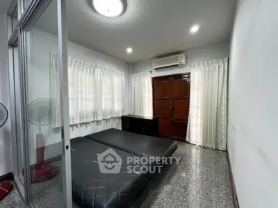 Spacious bedroom with modern design and ample natural light, featuring sleek flooring and air conditioning.