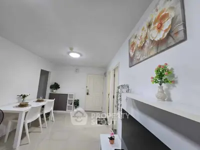 Modern living room with elegant decor and dining area, featuring stylish furniture and floral artwork.