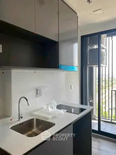 Modern kitchen with sleek cabinetry and balcony view, perfect for urban living.