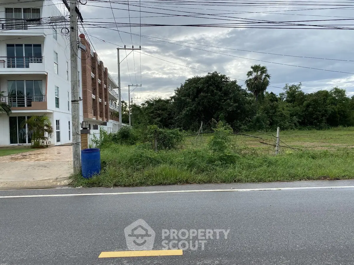 Prime real estate land with adjacent modern building and lush greenery, ideal for development opportunities.